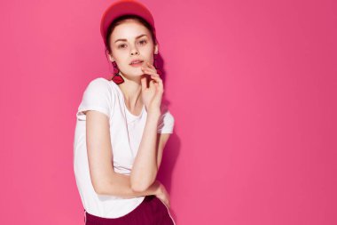 Kafasında şapkası olan, yaz kıyafetleri içinde güzel bir kadın. Eğlenceli pembe bir arka plan.