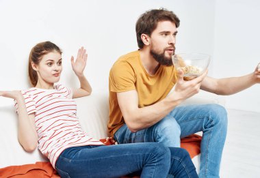 Aile evde kanepede oturup patlamış mısırla film seyrediyor.