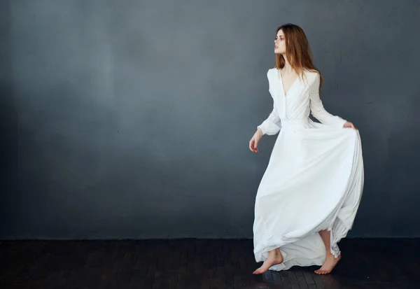Mujer en vestido blanco descalzo baile divertido fondo oscuro — Foto de Stock