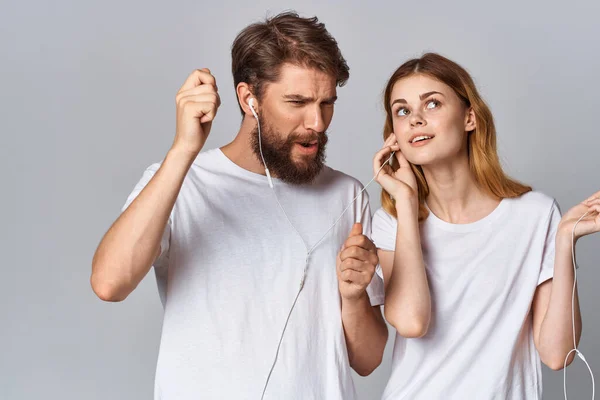 Mladý pár v bílých tričkách nošení sluchátek poslech hudby technologie zábavy — Stock fotografie