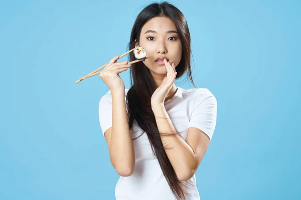 Азиатская женщина в белой футболке суши палочки для еды — стоковое фото