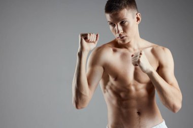 Gri arka planda şişirilmiş gövde boksu yapan sporcu kasları gördü.