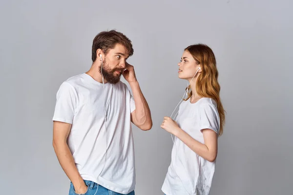 白いTシャツの男と女はヘッドフォンで友情音楽の隣に立っています — ストック写真