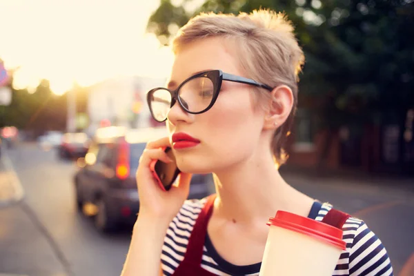 Mujer en la calle hablando por teléfono con una taza de café a pie — Foto de Stock