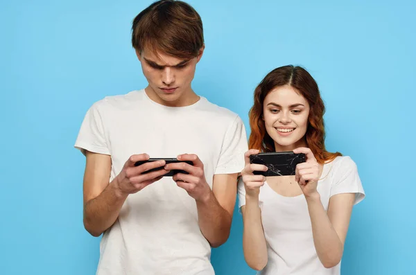 Giovane coppia in t-shirt bianche con telefoni in tecnologia mani — Foto Stock