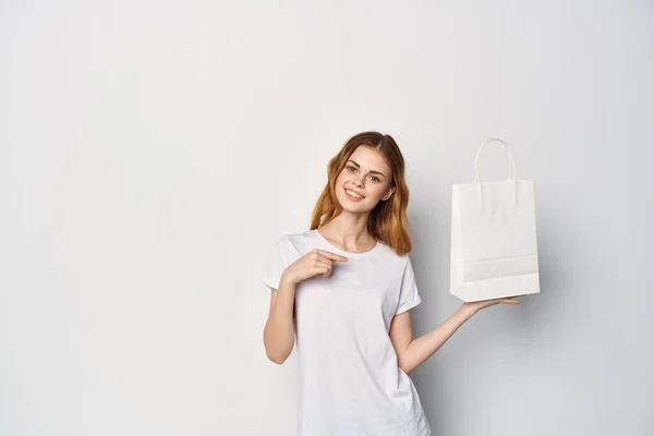 Mujer en una camiseta blanca con un paquete en sus manos haciendo gestos con sus manos maqueta — Foto de Stock
