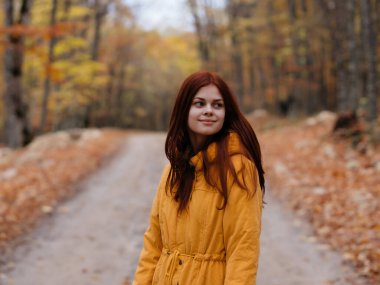 Sonbahar orman yürüyüşünde sarı ceketli kadın.