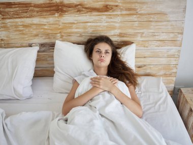 Üzgün kadın yatakta uzanıyor. Düşünceli yüz ifadesi. Uyku odası.