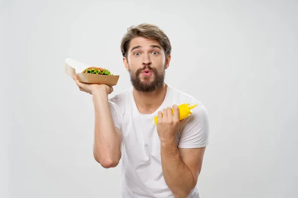 하얀 티셔츠 햄버거를 먹고 있는 남자 — 스톡 사진