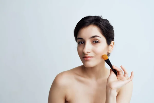 Woman with bare shoulders apply makeup on face makeup brush — Stock Photo, Image