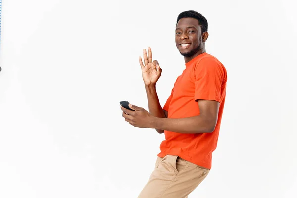 Homem emocional africano telefone celular gesticulando com as mãos e camiseta laranja — Fotografia de Stock