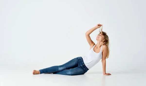 woman in jeans lies on the floor posing fashion light background