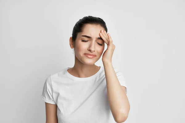 Brunette in een wit t-shirt met haar hoofd migraine stress depressie — Stockfoto