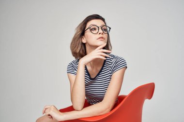 Sandalyede oturan güzel kadın. Moda kıyafetleri. Arka plan açık.