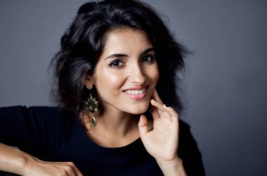 Gevşek saç küpeli güzel bir kadın yakın plan modellik yapıyor.