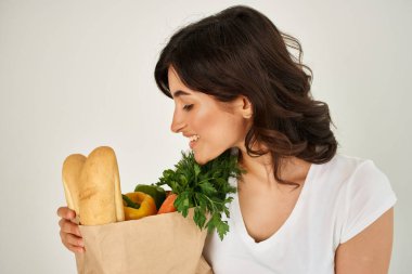 Esmer, beyaz tişörtlü, içinde bakkaliye ve sağlıklı yiyecek paketi olan. Yakın çekim.