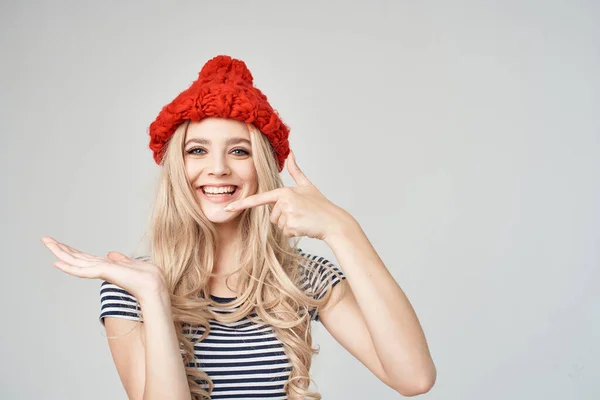 Bella bionda in un cappello rosso gesticolando con le mani di moda sfondo leggero — Foto Stock