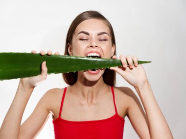 Yeşil aloe yaprağıyla mutlu bir kadın gözlerini kapattı cilt kozmetik dermatolojisini temizledi.