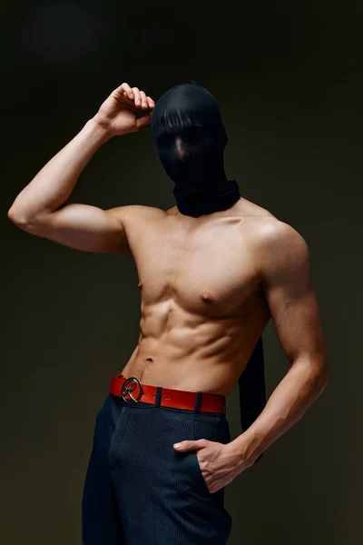 Hombre con músculos bombeados pastel culturista prensa gris fondo pantalones y máscara — Foto de Stock