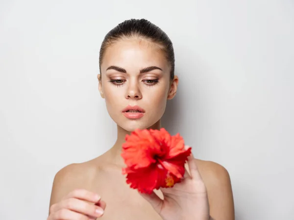 Nő kezében egy piros virág egy könnyű háttér — Stock Fotó