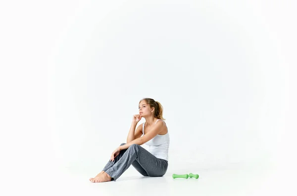 Спортсменка сидить на підлозі з зеленими гантелями тренування в спортзалі — стокове фото