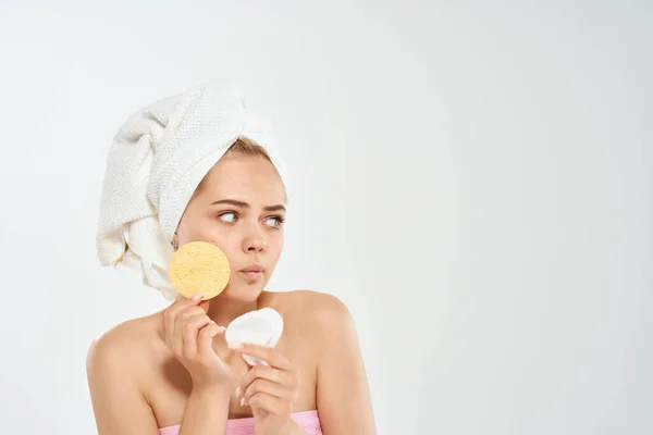 Frau mit nackten Schultern und einem Handtuch auf dem Kopf reinigt die Gesichtshaut — Stockfoto