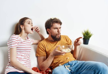 Aile evde kanepede oturup patlamış mısırla film seyrediyor.