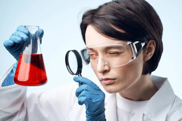 Mujer científica mirando a través de una lupa en una solución química trabajo biotecnología —  Fotos de Stock