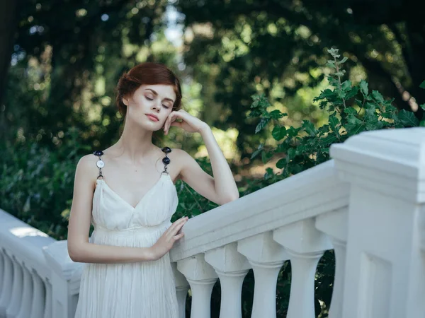 Bella donna dai capelli rossi in abito bianco in posa nel parco mitologia — Foto Stock