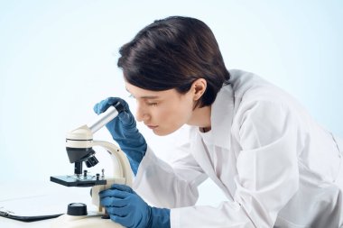 Bir kadın mikroskop üzerinden araştırma yapıyor.