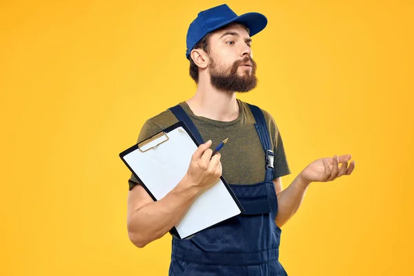 Man in work uniform with boxes delivery service yellow background — ストック写真