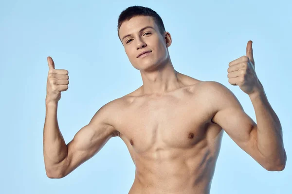 Sporty man with naked torso showing thumb on blue background — стоковое фото
