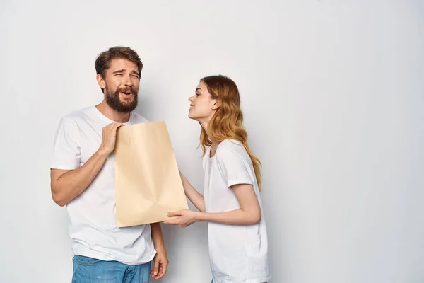 Νεαρό ζευγάρι σε λευκό t-shirts χάρτινη τσάντα πώληση ψώνια — Φωτογραφία Αρχείου