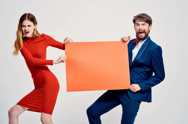 Erkek ve kadın ellerinde kırmızı maket uzay reklam afişi tutuyorlar. — Stok fotoğraf