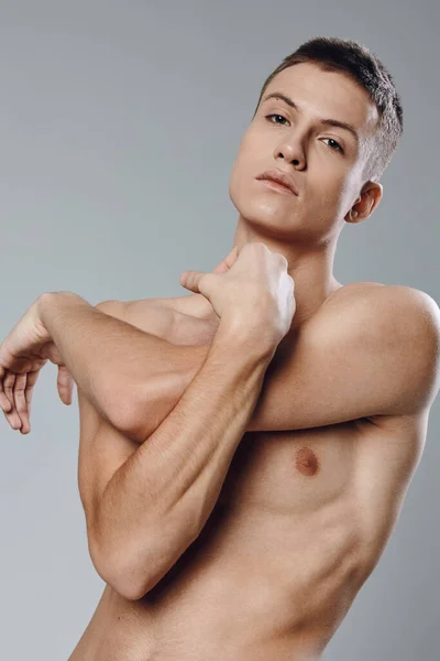 Guy twisted his arms on a gray background naked torso muscles biceps — Photo