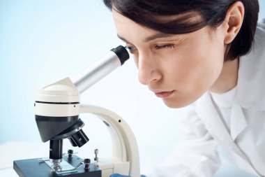 Tıbbi maske mikroskop analiz araştırmasında kadın laboratuvar asistanı.