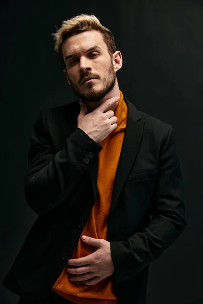 Blond man houdt hand op nek en oranje trui zwart jasje model — Stockfoto