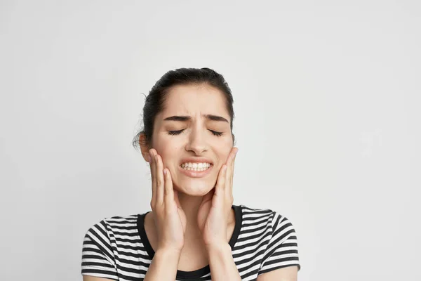 Mulher em t-shirt listrada segurando rosto dor desconforto odontologia — Fotografia de Stock