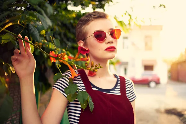 Vacker kvinna bär solglasögon utomhus blommor dekoration poserar — Stockfoto