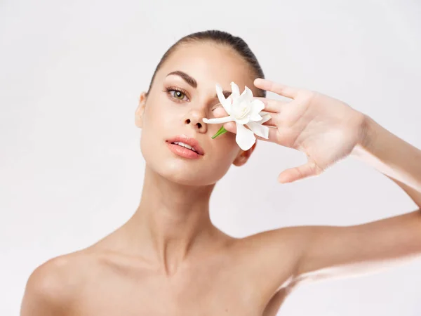 Mujer con hombros desnudos flor blanca cosméticos piel limpia — Foto de Stock