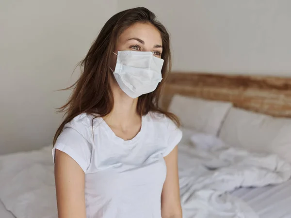 Mulher em máscara médica sentado na cama e olhando para o lado recortado vista — Fotografia de Stock