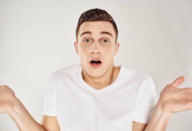 Beyaz tişörtlü şaşırmış bir adam ellerini havaya kaldırıyor. Duygularını açığa vuruyor.