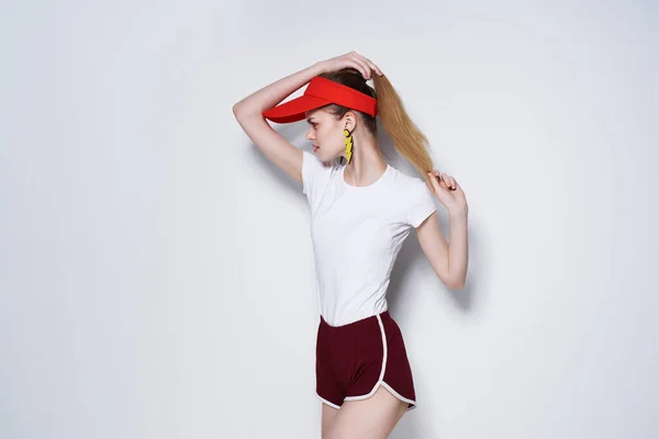 Мила дівчина в червоній шапці і шорти літня мода позує світлий фон — стокове фото