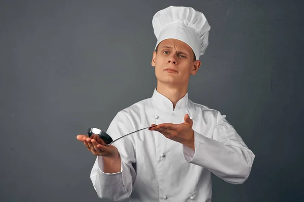 Chef con un mestolo in mano sta cercando piatti ristorante professionale — Foto Stock