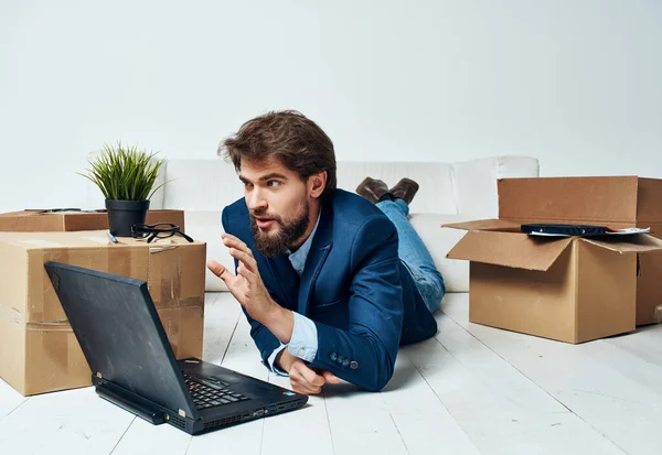 Un homme en costume se trouve sur le sol dans des boîtes avec des choses ordinateur portable manager professionnel — Photo