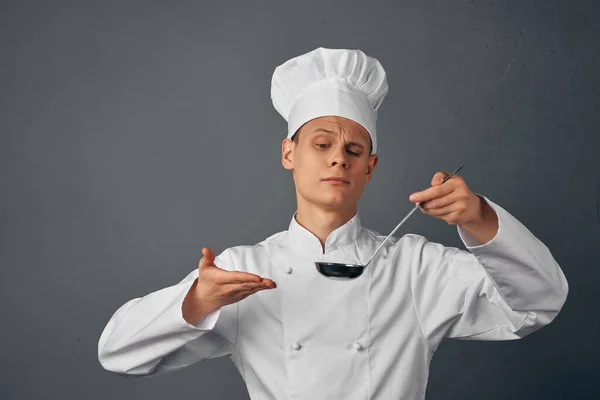 Un cuoco con un mestolo in mano sta provando un piatto da ristorante cucina professionale — Foto Stock
