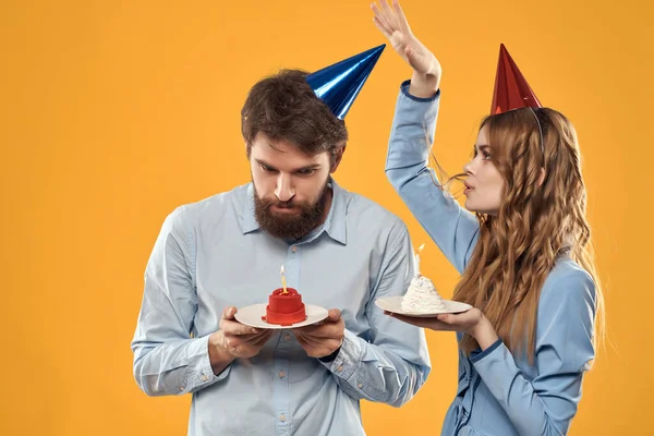 Joven pareja cumpleaños fiesta divertido tapas en la cabeza amarillo fondo — Foto de Stock