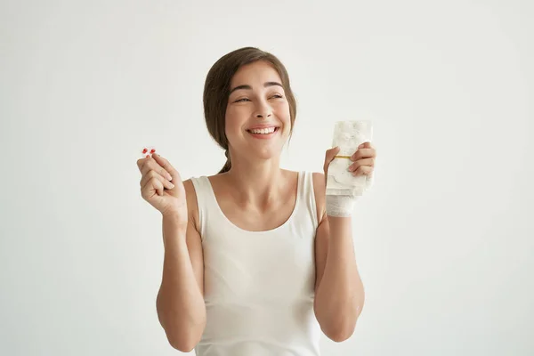 Mujer con pastillas en las manos en camiseta blanca medicina de salud de la mano lesionada — Foto de Stock