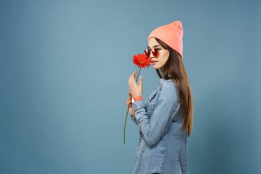 Elinde kırmızı çiçekli bir kadın pembe şapkalı şık elbiseli cazibeli bir kadın.