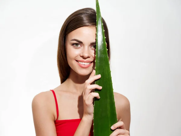 Happy woman with green aloe leaf on light background and red t-shirt cropped view model — Fotografia de Stock